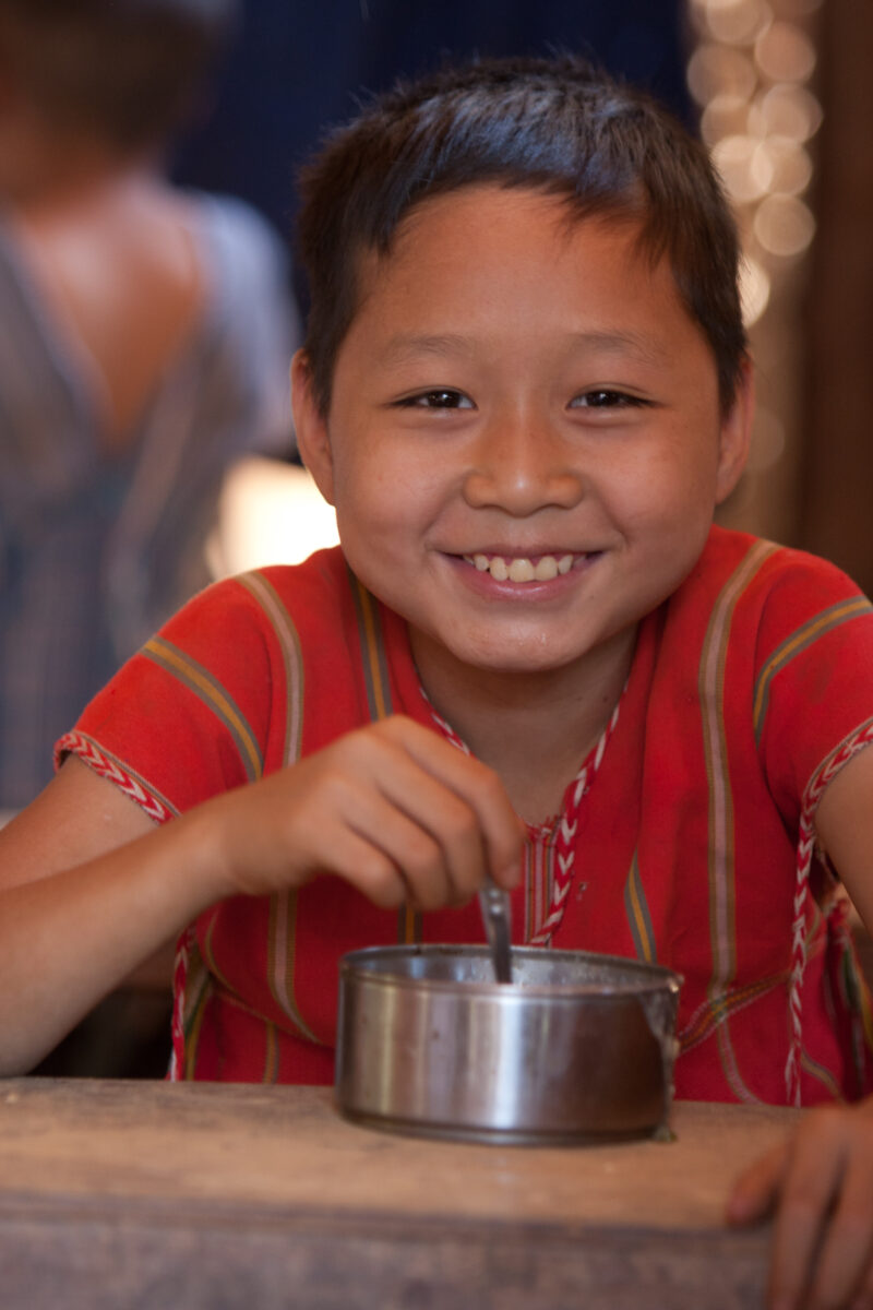 Getting a Hot Meal at School — Children eat a bowl of hot soup, as part of their school feeding program, at a Karen refugee camp, near the Thai border with M...