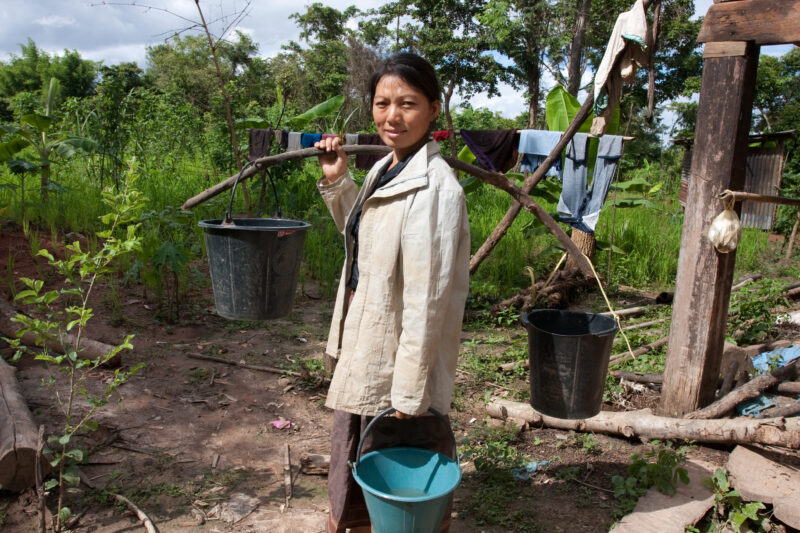 Collecting Water in Laos — Woman heads to the pump for water, with all her pails. — Laos, Southeast Asia, woman, water, collecting water
