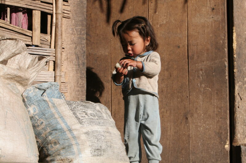 Baby in Doorway in Laos — Ethnic minority baby in a village in Northern Laos holding sticky Rice. — Laos, Southeast Asia, child, children, baby