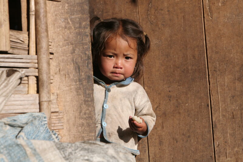 Baby in Doorway in Laos — Ethnic minority baby in a village in Northern Laos holding sticky Rice. — Laos, Southeast Asia, child, children, baby
