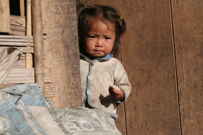 Baby in Doorway in Laos — Ethnic minority baby in a village in Northern Laos holding sticky Rice. — Laos, Southeast Asia, child, children, baby