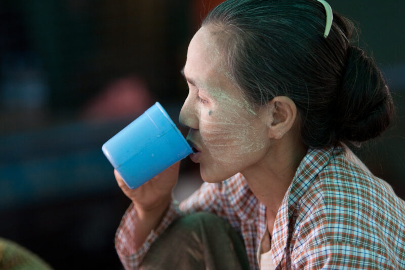 Woman Drinks — Woman with thanakha on her face — ADRA, Burma, Myanmar, face, faces
