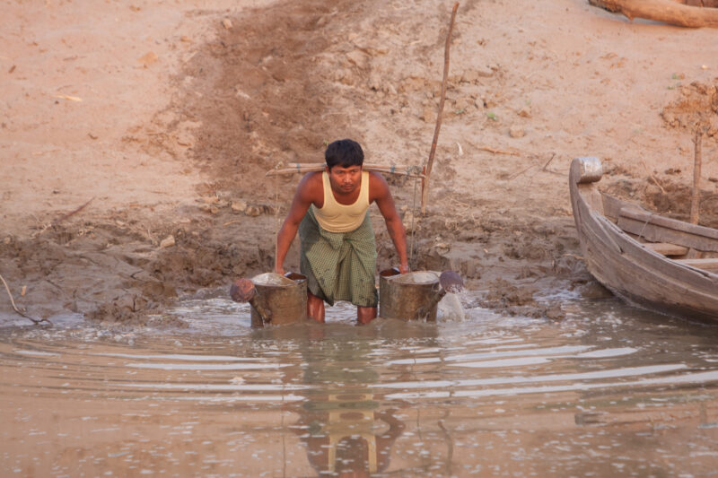 Collecting Water — Man scoops up water from the Ayeyarwaddy river in Burma, to irrigate his garden — Burma, Myanmar, man, water, river