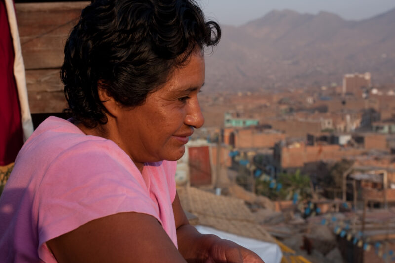 Living in Poverty — Profile of a mother and her two children living in one of the poor communities on the outskirts of Lima, Peru: Woman stands on the porch ...