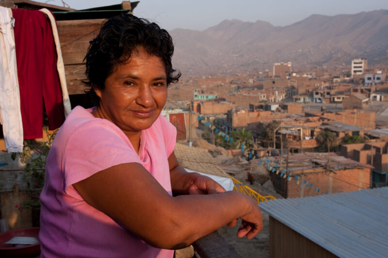 Living in Poverty — Profile of a mother and her two children living in one of the poor communities on the outskirts of Lima, Peru: Woman stands on the porch ...