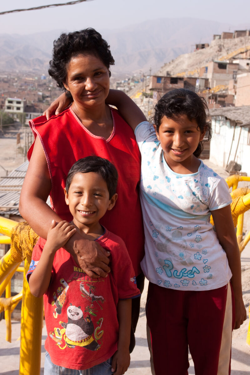 Living in Poverty — Profile of a mother and her two children living in one of the poor communities on the outskirts of Lima, Peru: by their home — Peru, slum...