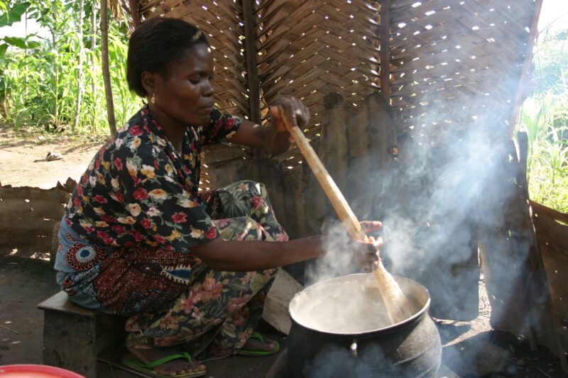 Cooking Food on open fire in Togo — Woman cooks a meal over an open fire in her outdoor kitchen in rural Togo, West Africa. — Togo, Africa, West Africa, face...