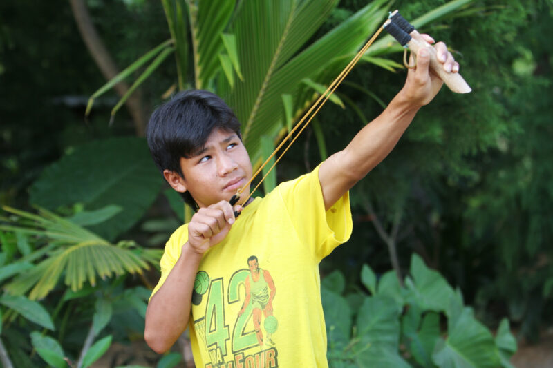 Boy with Sling Shot — Boy takes aim with his slingshot, hoping to bring down some game for the evening meal for his family in rural Thailand — Thailand, boy,...