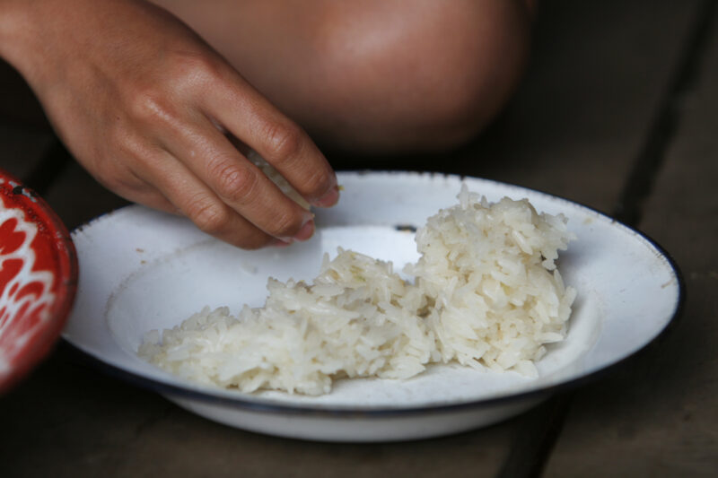 Rice for the Eating — Closeup of hand reaching into plate of rice. — Thailand, food, eating, rice, bowl