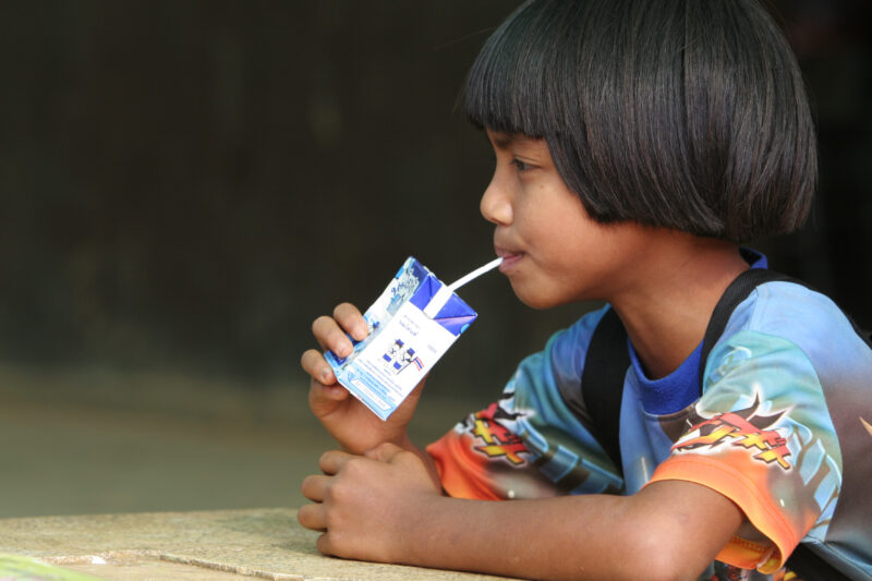 Girl with Juice Box — Girl sips milk from a milk box, at her school in Thailand — Thailand, children, students, school, milk
