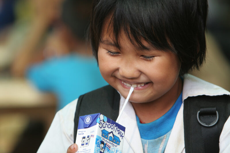 Girl with Juice Box — Girl sips milk from a milk box, at her school in Thailand — Thailand, children, students, school, milk
