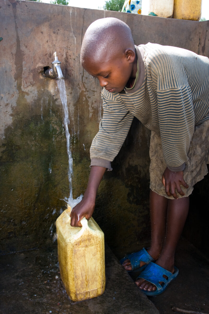 Collecting Water — Girl gets water from a gravity fed water system installed by ADRA. — Africa, Rwanda, girl, collecting water, water system