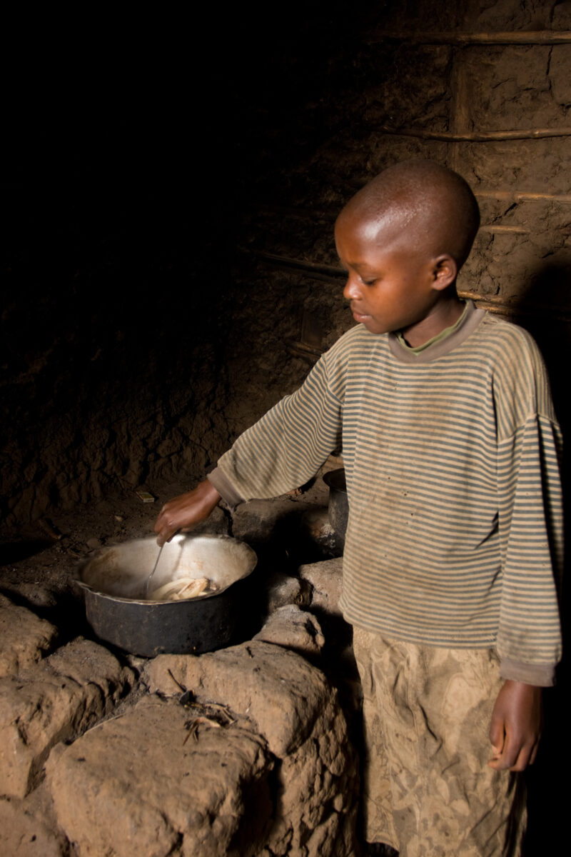 Cooking In Rwanda — Young girls cooks for the family over a open fire on a stove made of mud bricks. — Africa, Rwanda, food, cooking, girl
