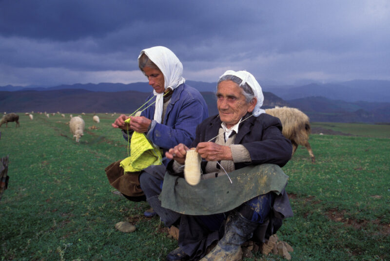 Elder woman in Albania — Elderly Albanian women knit in the field, while watching their sheep as a storm aproaches — Albania, Albanian, woman, women, knitting
