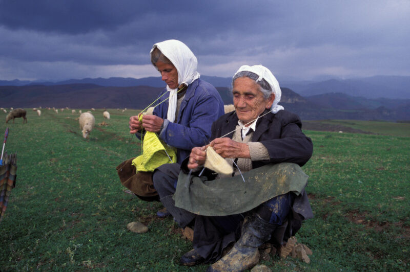 Elder woman in Albania — Elderly Albanian women knit in the field, while watching their sheep as a storm aproaches — Albania, Albanian, woman, women, knitting