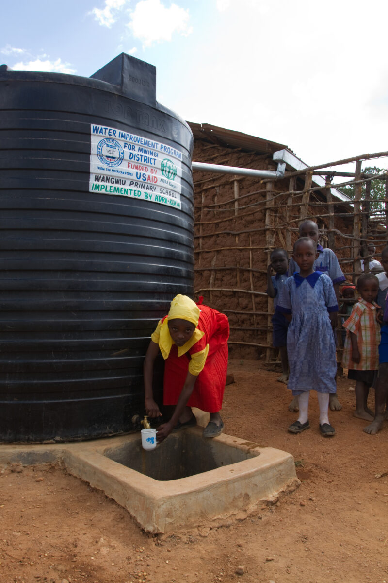 Water Storage Tank — In a remote rural school in Kenya, students enjoy the convenience of drinking water from a storage tank provided by ADRA, located right ...
