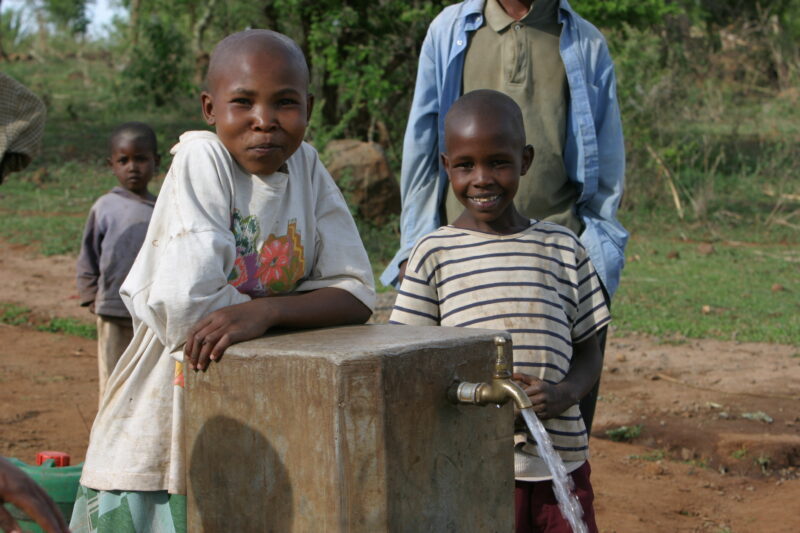At the Water Tap in Tanzania — People living in Hanang District of Tanzania, now enjoy an extensive, gravity fed water system that brings water from mountain...