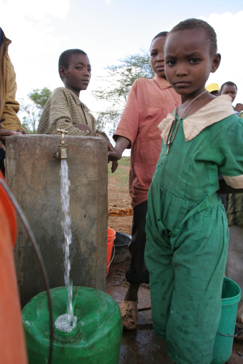 At the Water Tap in Tanzania — People living in Hanang District of Tanzania, now enjoy an extensive, gravity fed water system that brings water from mountain...
