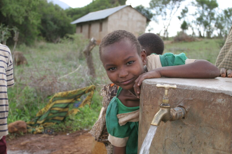 At the Water Tap in Tanzania — People living in Hanang District of Tanzania, now enjoy an extensive, gravity fed water system that brings water from mountain...