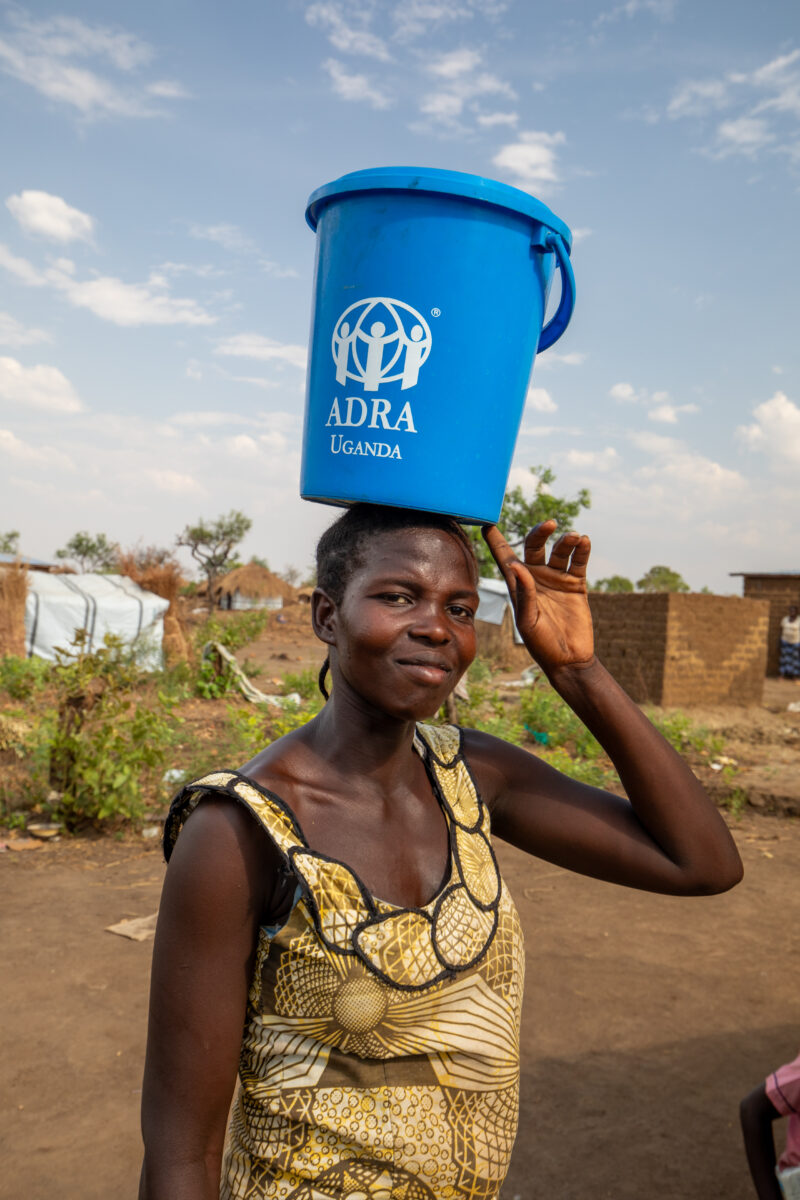 Woman with Water Pail — Collecting water at the Refugee Settlement — Child, Complementary Colors, Eyes Open, Frontal Face, Male