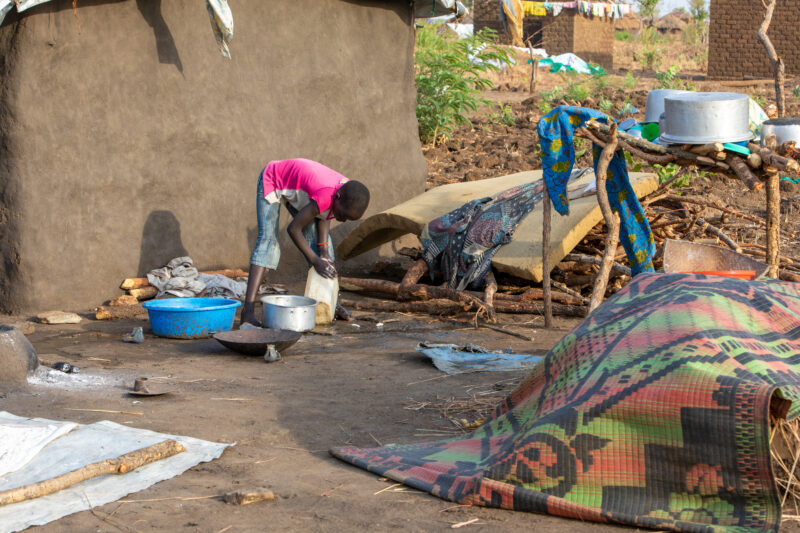 Washing Dishes — Young refugee girl washes dishes in her new home in Uganda. — Person, Refugee, Refugee Settlement, South Sudan
