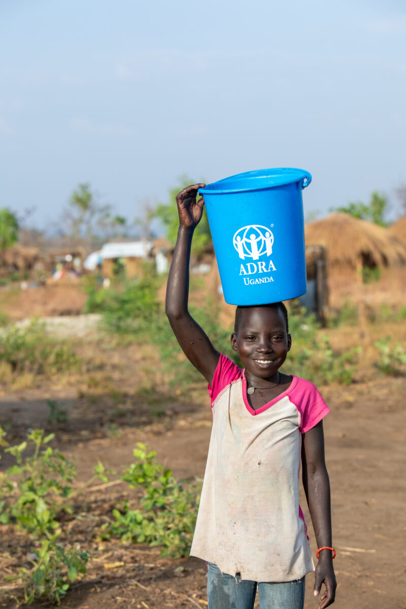 Collecting Water in the Refugee Settlement — Refugee girl collects water in her new home at a Refugee Settlement in Uganda — Child, Eyes Open, Female, Fronta...