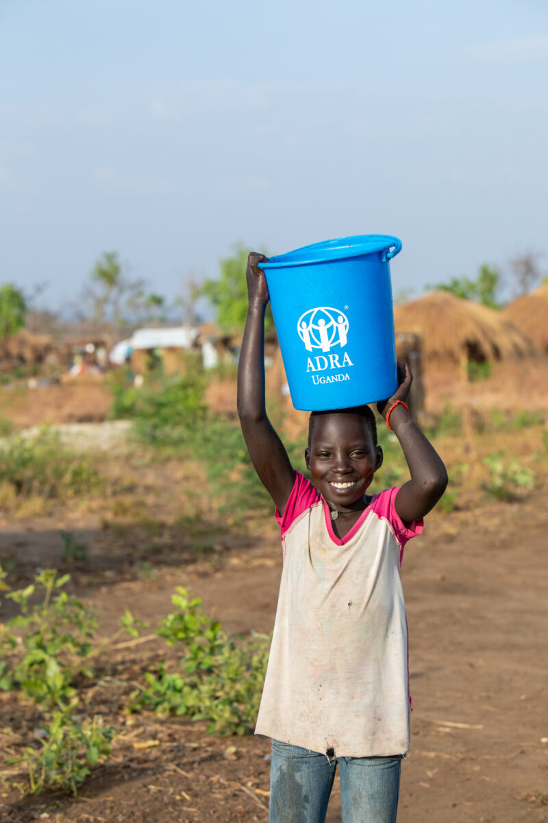 Collecting Water in the Refugee Settlement — Refugee girl collects water in her new home at a Refugee Settlement in Uganda — Child, Eyes Open, Female, Fronta...
