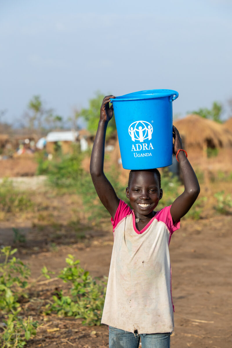 Collecting Water in the Refugee Settlement — Refugee girl collects water in her new home at a Refugee Settlement in Uganda — Child, Eyes Open, Female, Fronta...