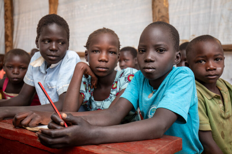 School in the Refugee Settlement — Refugee Children attend school at the refugee settlement they call their new home. — Adult, Boat, Child, Eyes Open, Female