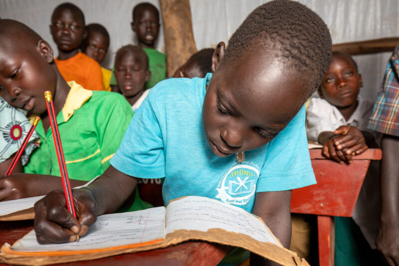 School in the Refugee Settlement — Refugee Children attend school at the refugee settlement they call their new home. — Adult, Beard, Eyes Closed, Eyes Open,...