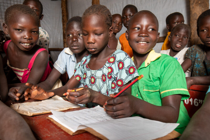 School in the Refugee Settlement — Refugee Children attend school at the refugee settlement they call their new home. — Adult, Child, Eyes Closed, Eyes Open,...