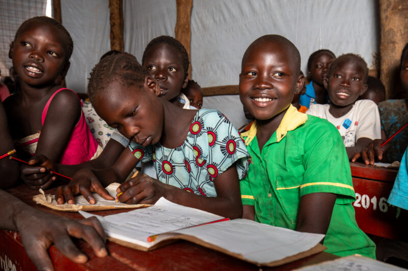 School in the Refugee Settlement — Refugee Children attend school at the refugee settlement they call their new home. — Adult, Eyes Open, Female, Frontal Fac...