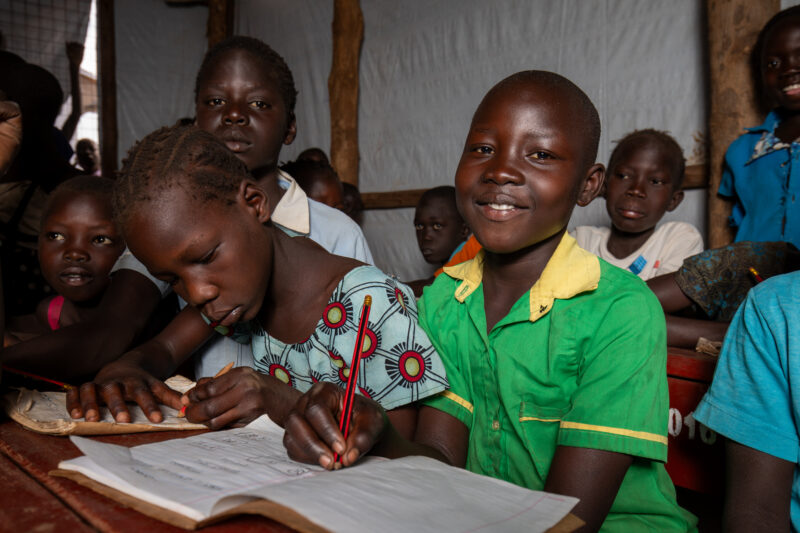 School in the Refugee Settlement — Refugee Children attend school at the refugee settlement they call their new home. — Adult, Eyes Open, Female, Frontal Fac...