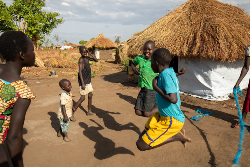 Skipping in a Refugee Settlement — Refugee kids from South Sudan, play games in their new home in Uganda. — Adult, Child, Eyes Open, Female, Frontal Face
