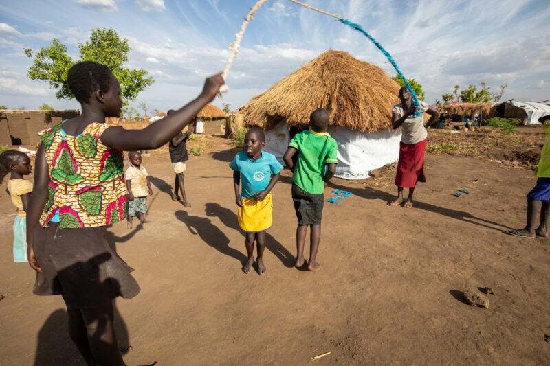 Skipping in a Refugee Settlement — Refugee kids from South Sudan, play games in their new home in Uganda. — Child, Eyes Closed, Female, Frontal Face, Group