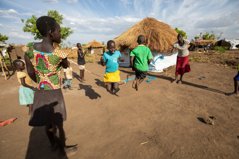 Skipping in a Refugee Settlement — Refugee kids from South Sudan, play games in their new home in Uganda. — Child, Eyes Closed, Female, Frontal Face, Person