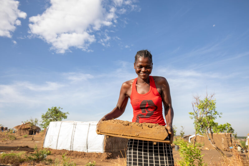 Making Bricks — South Sudan refugee woman makes mud bricks for the house that she is building at the refugee setllement. — Athletics, Complementary Colors, F...