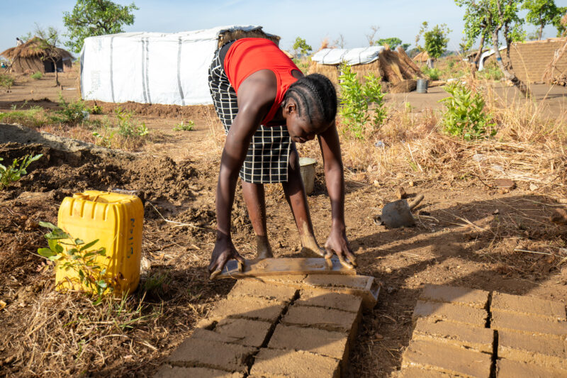 Making Bricks — South Sudan refugee woman makes mud bricks for the house that she is building at the refugee setllement. — Person, Refugee, Refugee Settlemen...