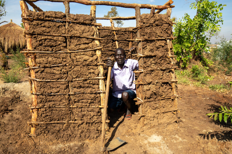 Making a Latrine — Refugee man makes a latrine by his new home in a refugee Settlement in Uganda — Elderly, Eyes Open, Frontal Face, Male, One Face