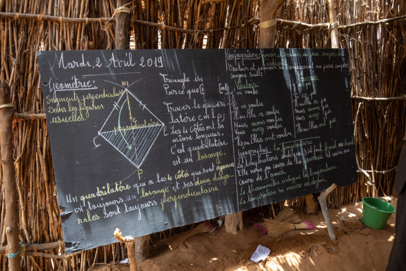 Temporary Classroom — Students in Niger, Africa, attend school in a classroom made of mud and sticks. — Africa, Education, Niger, Text