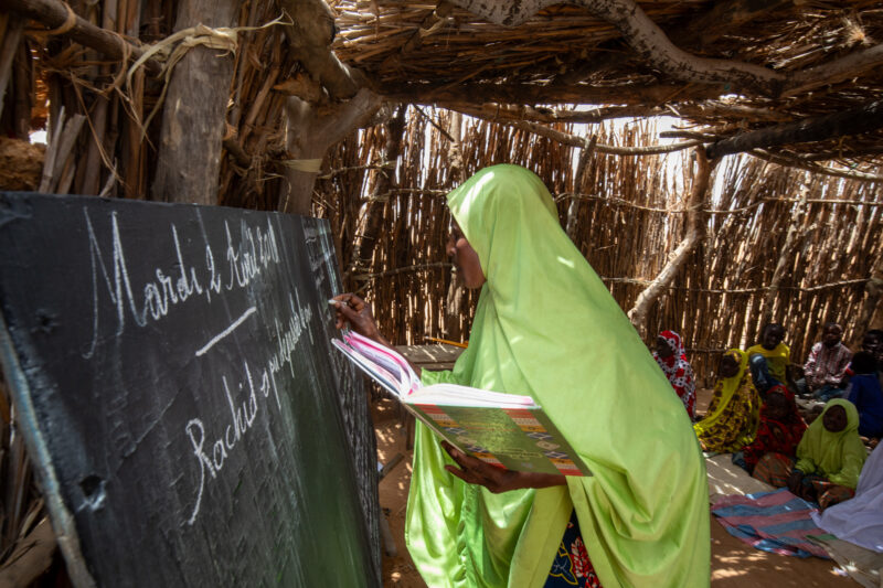 Temporary Classroom — Students in Niger, Africa, attend school in a classroom made of mud and sticks. — Africa, Education, Niger, Person, Text