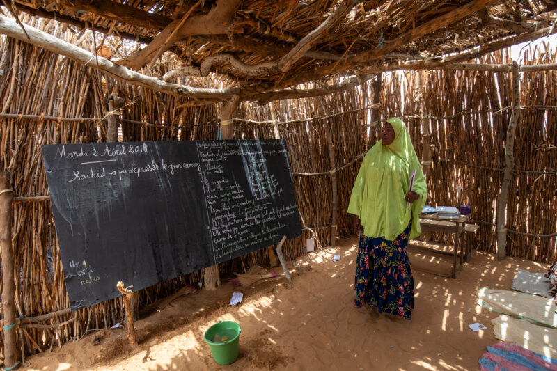 Temporary Classroom — Students in Niger, Africa, attend school in a classroom made of mud and sticks. — Adult, Africa, Education, Eyes Open, Female