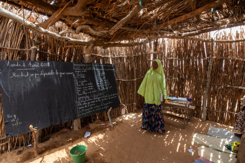 Temporary Classroom — Students in Niger, Africa, attend school in a classroom made of mud and sticks. — Adult, Africa, Education, Eyes Open, Frontal Face