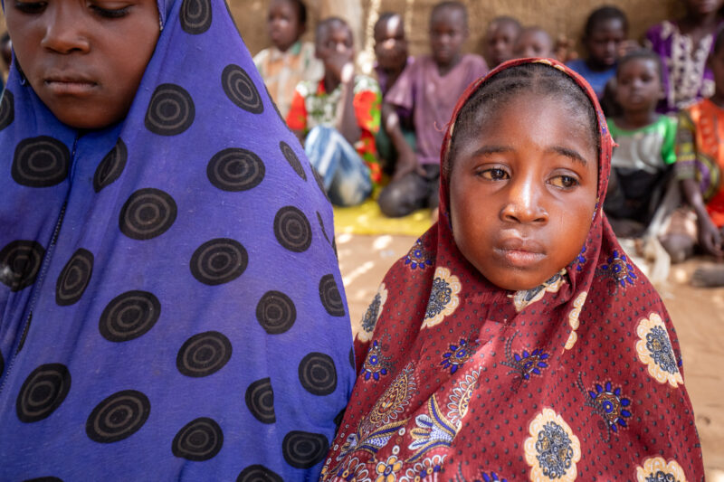 Temporary Classroom — Students in Niger, Africa, attend school in a classroom made of mud and sticks. — Adult, Africa, Child, Education, Eyes Closed