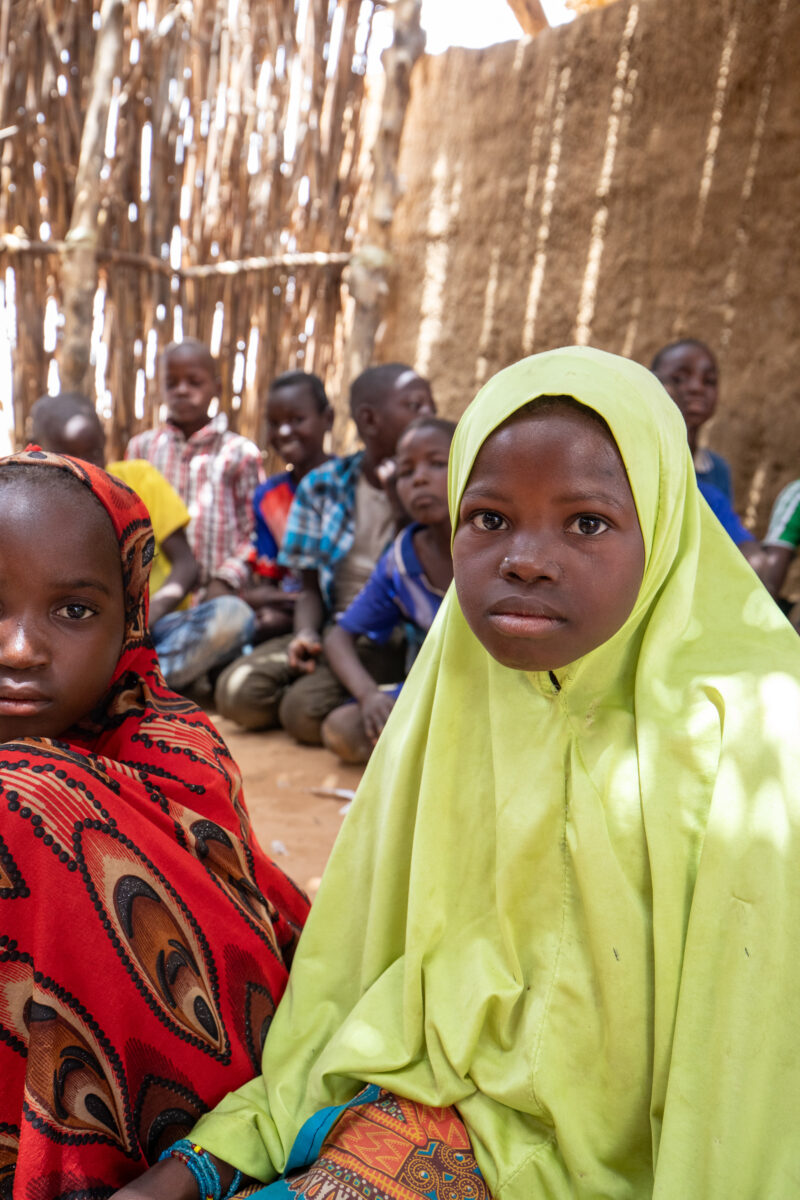 Temporary Classroom — Students in Niger, Africa, attend school in a classroom made of mud and sticks. — Africa, Education, Eyes Open, Female, Frontal Face