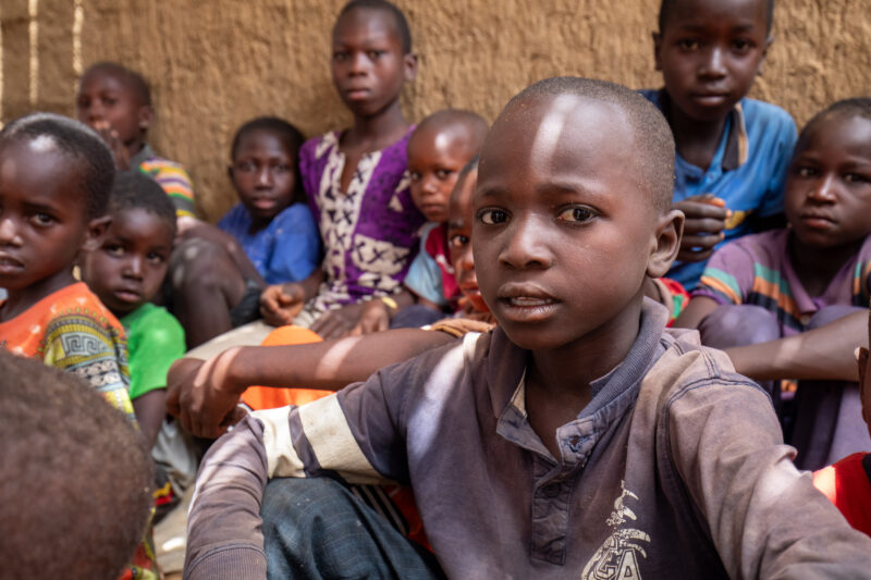Temporary Classroom — Students in Niger, Africa, attend school in a classroom made of mud and sticks. — Adult, Africa, Child, Education, Eyes Closed