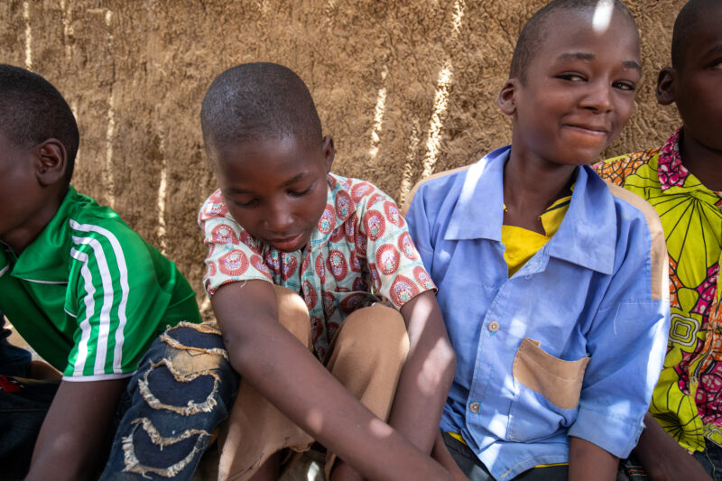 Temporary Classroom — Students in Niger, Africa, attend school in a classroom made of mud and sticks. — Adult, Africa, Child, Education, Eyes Closed