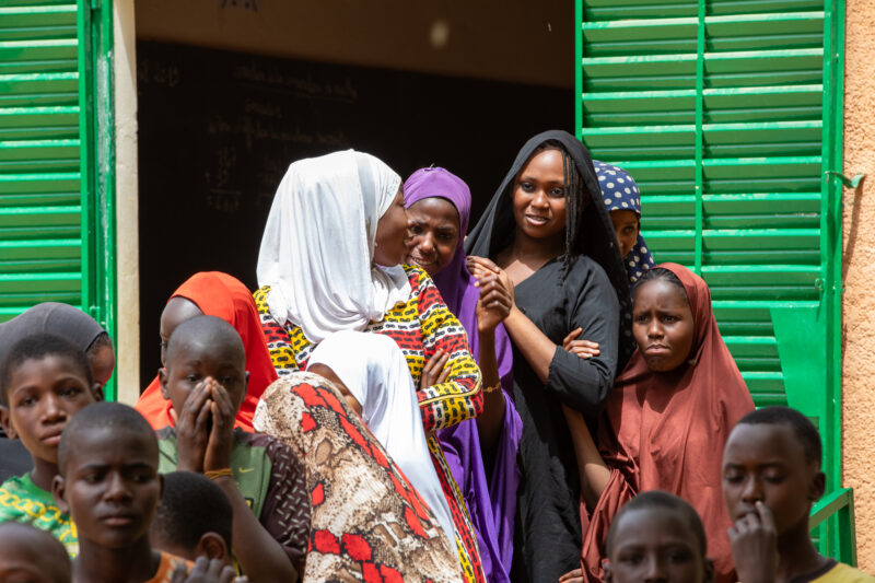 Students Outside their New School — Happy Student stand outside their new school provided by ADRA Norway — Adult, Africa, Beard, Complementary Colors, Education