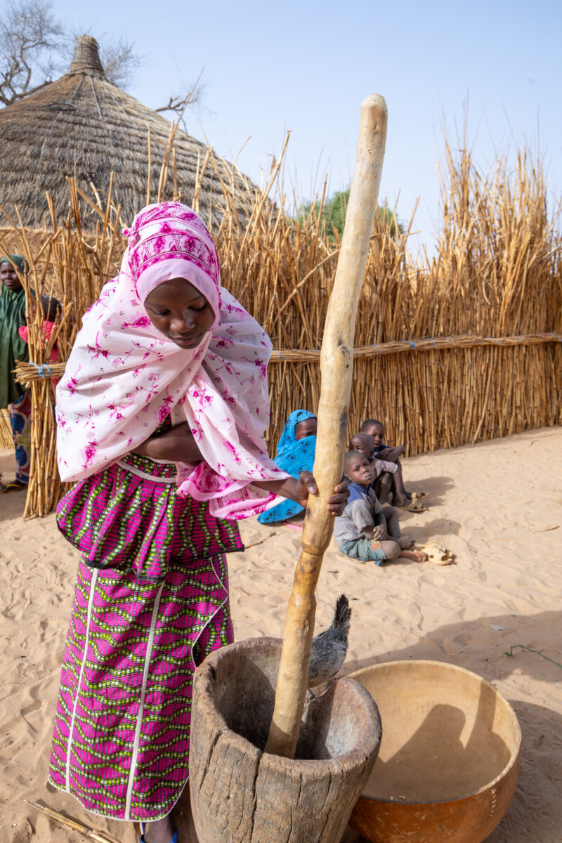 Pounding the Meal — Girl pounds sorgum into powder with a pounding stick — Adult, Africa, Beard, Child, Education
