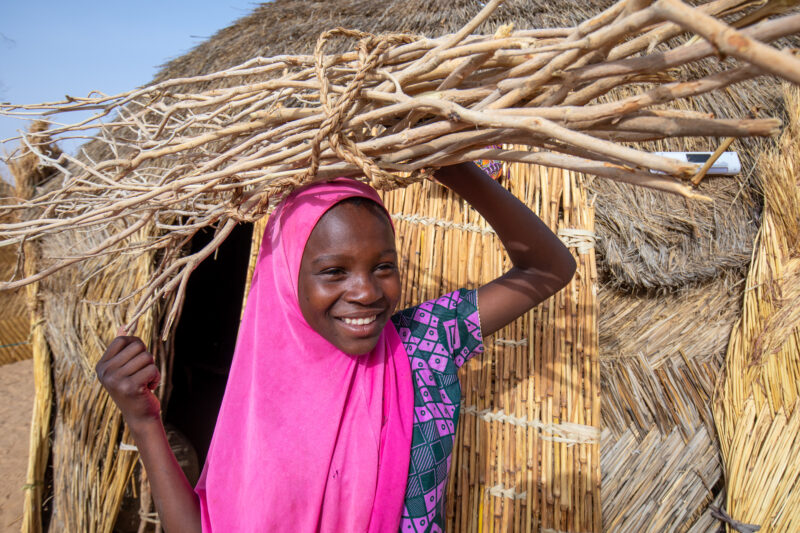 Collecting Firewood — Girl with the firewood that she has collected to cook the meal. — Africa, Child, Education, Eyes Open, Female